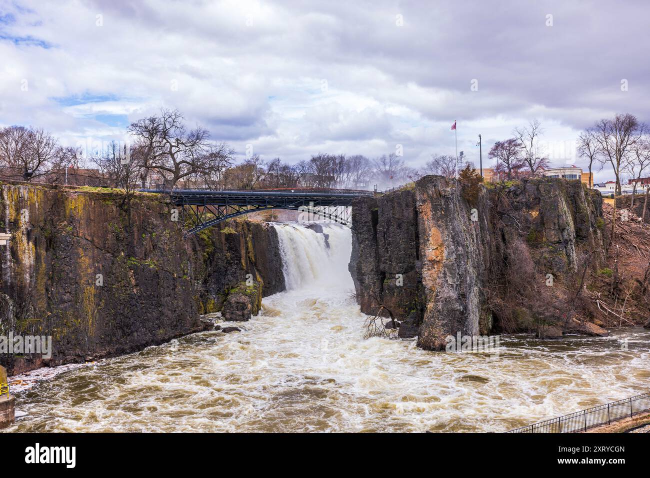 Paesaggio primaverile nel New Jersey con le Paterson Falls che scendono lungo il fiume Passaic, incorniciate da paesaggi di montagna e cielo nuvoloso. Foto Stock