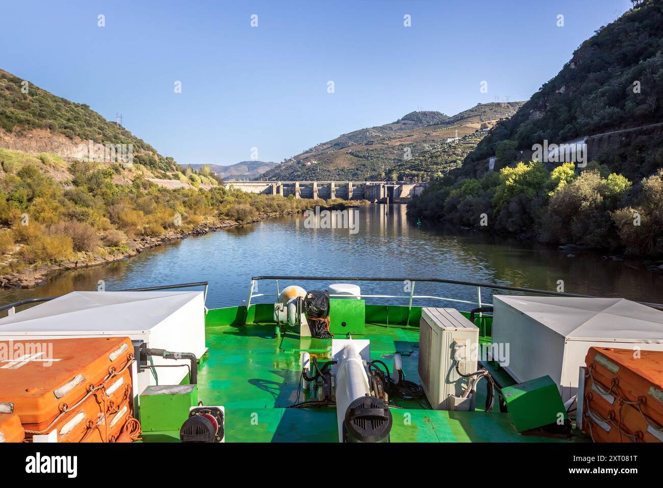 Vista dalla cima di una barca da crociera sul fiume Douro in Portogallo, con il fiume e la diga di Régua come sfondo in una giornata di sole. Foto Stock