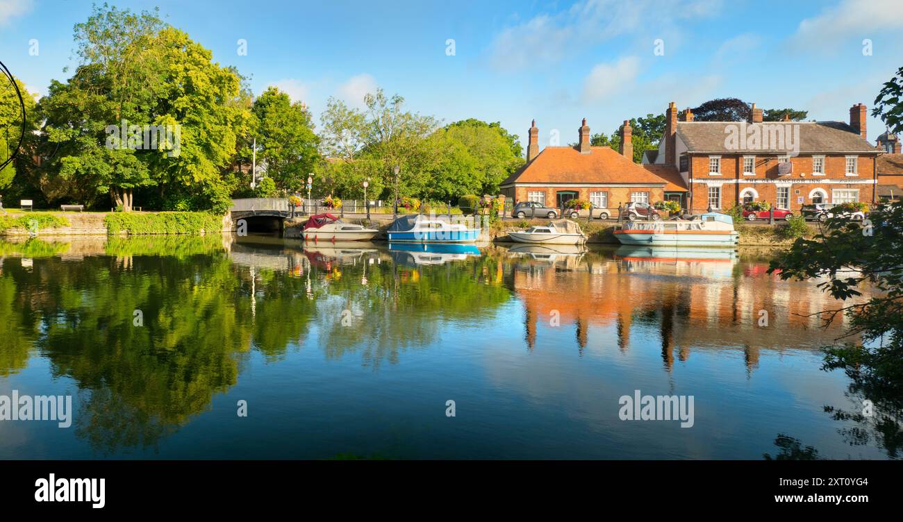 Saint Helen's Wharf è un famoso luogo di bellezza sul Tamigi, appena a monte del ponte medievale di Abingdon-on-Thames. Il molo è stato per secoli un importante collegamento di trasporto e trasporto marittimo sul Tamigi e tra i canali da Oxford e le Midlands. Belle case mercantili si incrociano con case di elemosina e la chiesa di Sant'Elena di epoca sassone. Qui vedremo imbarcazioni da diporto e case ormeggiate lungo le Long Alley Alms Houses, viste in una bella giornata di mezza estate dalla riva nord del fiume. Foto Stock