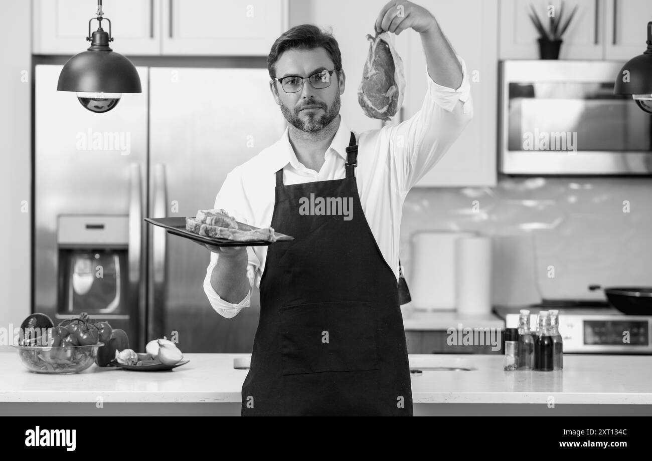 Chef che cucinano filetto di carne cruda in cucina. Concetto di menu del ristorante. Ritratto maschile dello chef uomo tenere la carne in cucina. Filetto di carne cruda per Foto Stock