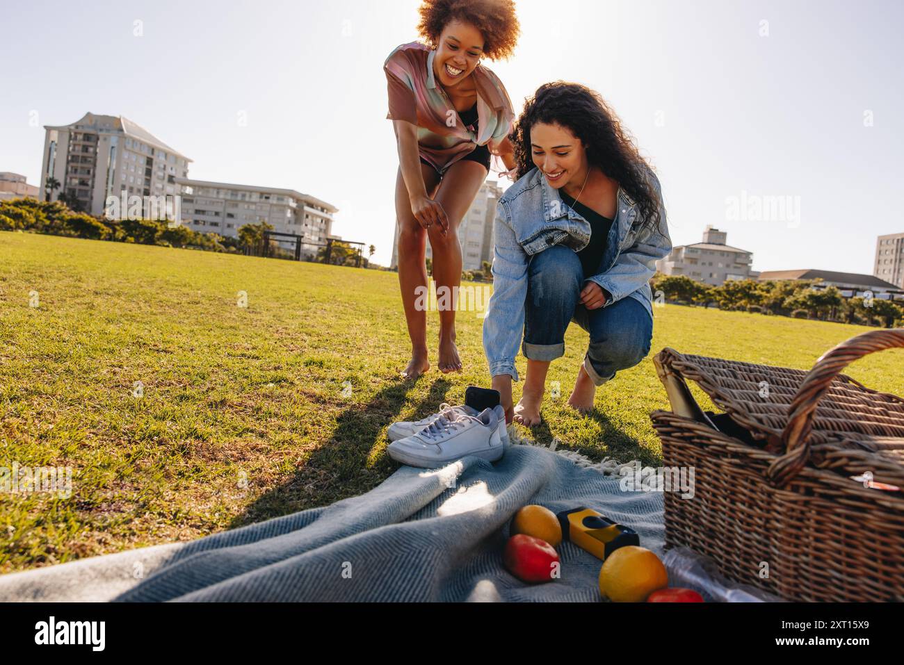 Due amici di gen-z stanno facendo un picnic divertente in un parco urbano e ballano di fronte a una telecamera per cellulari per i social media. Foto Stock