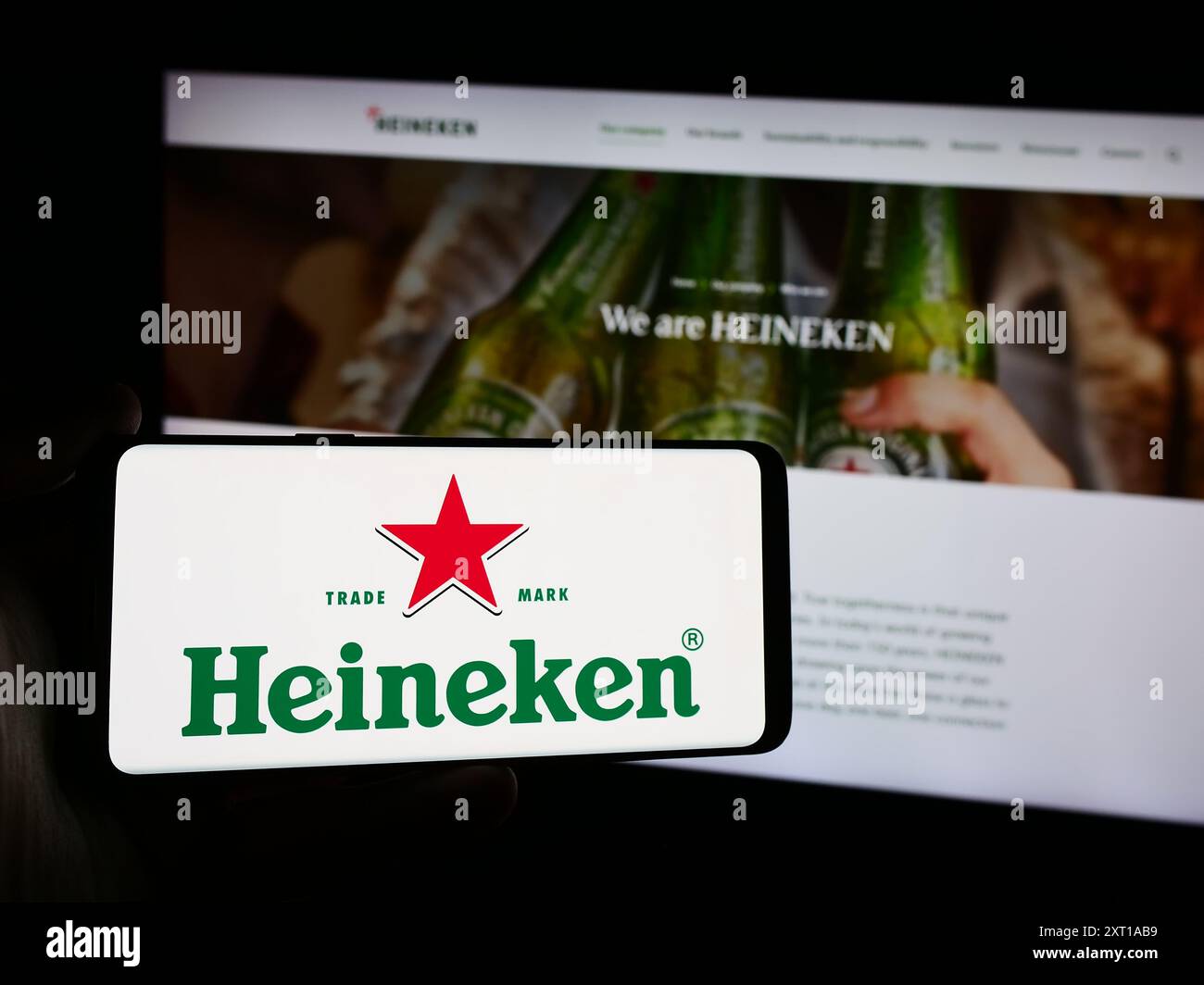 Persona che possiede uno smartphone con il logo della società olandese Heineken N.V. davanti al sito web. Mettere a fuoco il display del telefono. Foto Stock