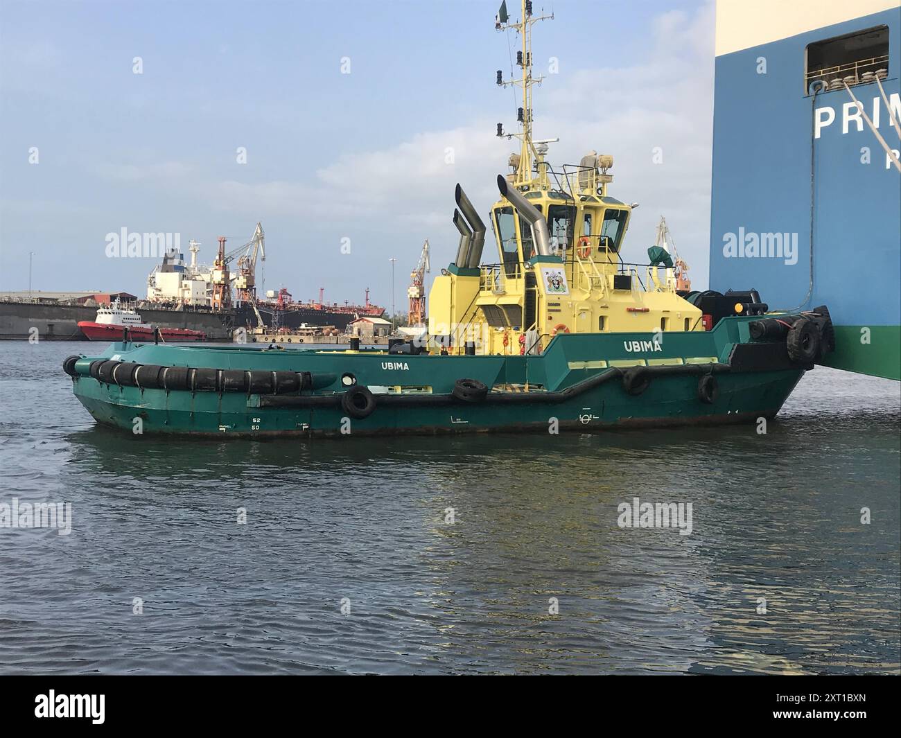ANCHE IL TUGBOAT È AL LAVORO, ORMEGGIANDO UNA NAVE ALL'ORMEGGIO. Foto Stock