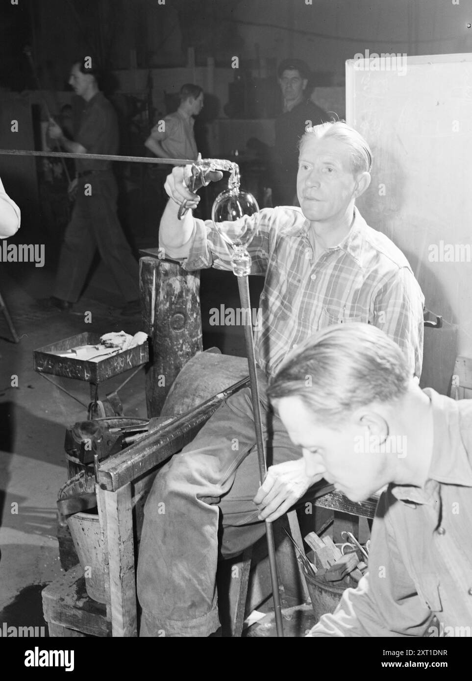 Effettivo 02- 1951: Processo di creazione a 1200 gradi. Hadelands Glassverk è il nostro più grande produttore di tutti i tipi di vetro per usi generici. L'azienda produce 3-4.000 diversi articoli di vetro, ma anche se la produzione annuale è fino a 6 milioni di pezzi, molti altri vengono schiacciati ogni anno. In breve tempo, tuttavia, i nuovi lavori di costruzione della vetreria di Hadeland saranno terminati, e l'aumento della produzione che ne deriverà significa che speriamo che il vetro possa essere presto cancellato dalla lista dei prodotti scarsamente disponibili. Il maestro Sverre Baskerud mette piede su un bicchiere da dessert. Foto: Aktuell / NTB ***la foto non è un processo di elaborazione dell'immagine Foto Stock