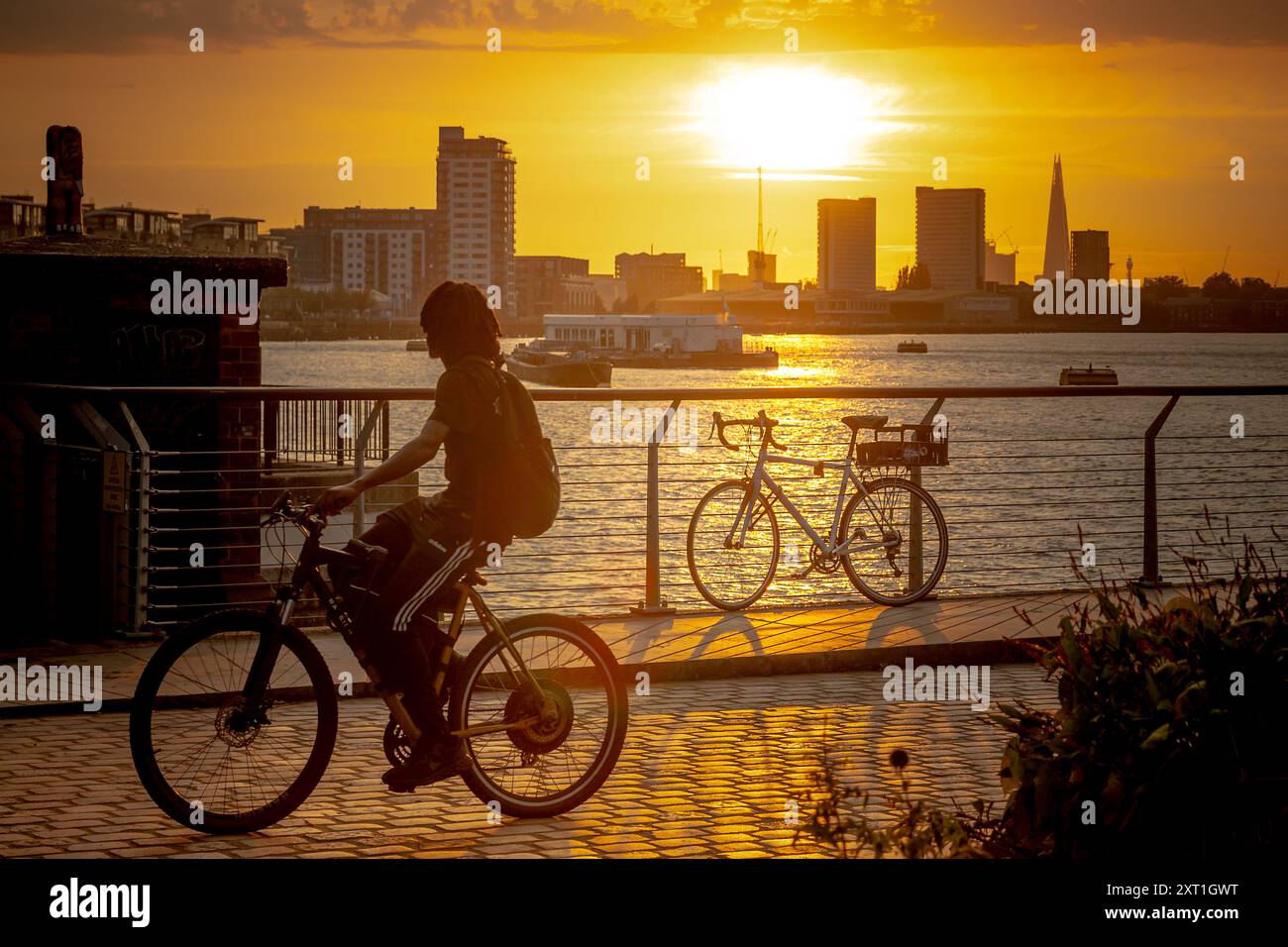 Londra, Regno Unito. 12 agosto 2024. Meteo nel Regno Unito: Il caldo sole della sera tramonta sul Tamigi nella zona est di Londra visto da Greenwich, concludendo il giorno più caldo dell'anno finora. Una temperatura di 34 °C (94 °F) è stata registrata a Cambridge, ha detto il MET Office. L'agenzia meteorologica ha dichiarato: "In via provvisoria questo è solo l'undicesimo anno dal 1961 in cui sono state registrate temperature così alte”. Crediti: Guy Corbishley/Alamy Live News Foto Stock