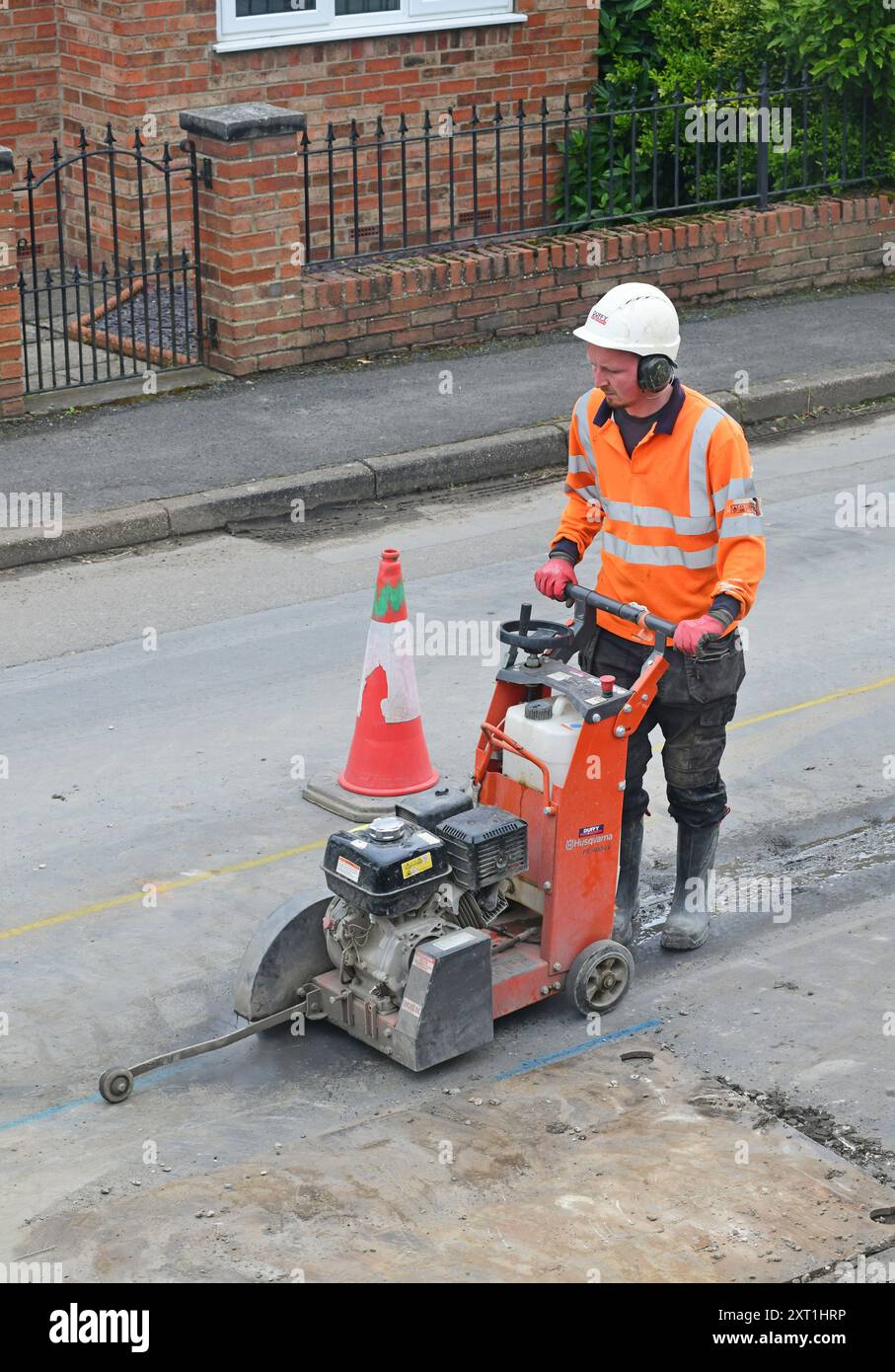 Ingegneri che utilizzano la taglierina stradale e installano una nuova linea di tubi sotto la strada principale per fermare le inondazioni nel villaggio di Ellerton York Yorkshire Regno Unito Foto Stock