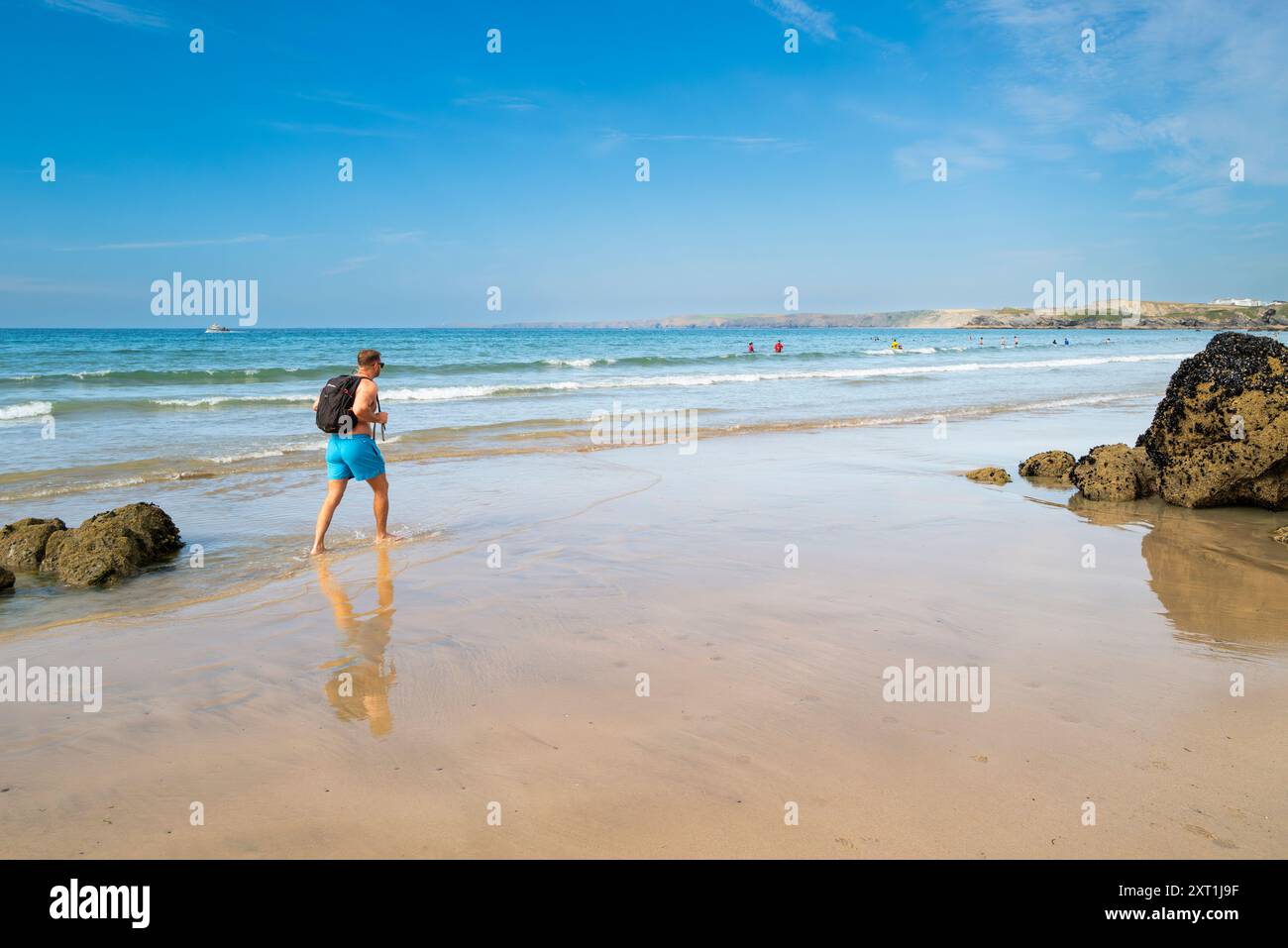 Un turista che si gode una passeggiata lungo la riva di Towan Beach a Newquay, in Cornovaglia, nel Regno Unito. Foto Stock