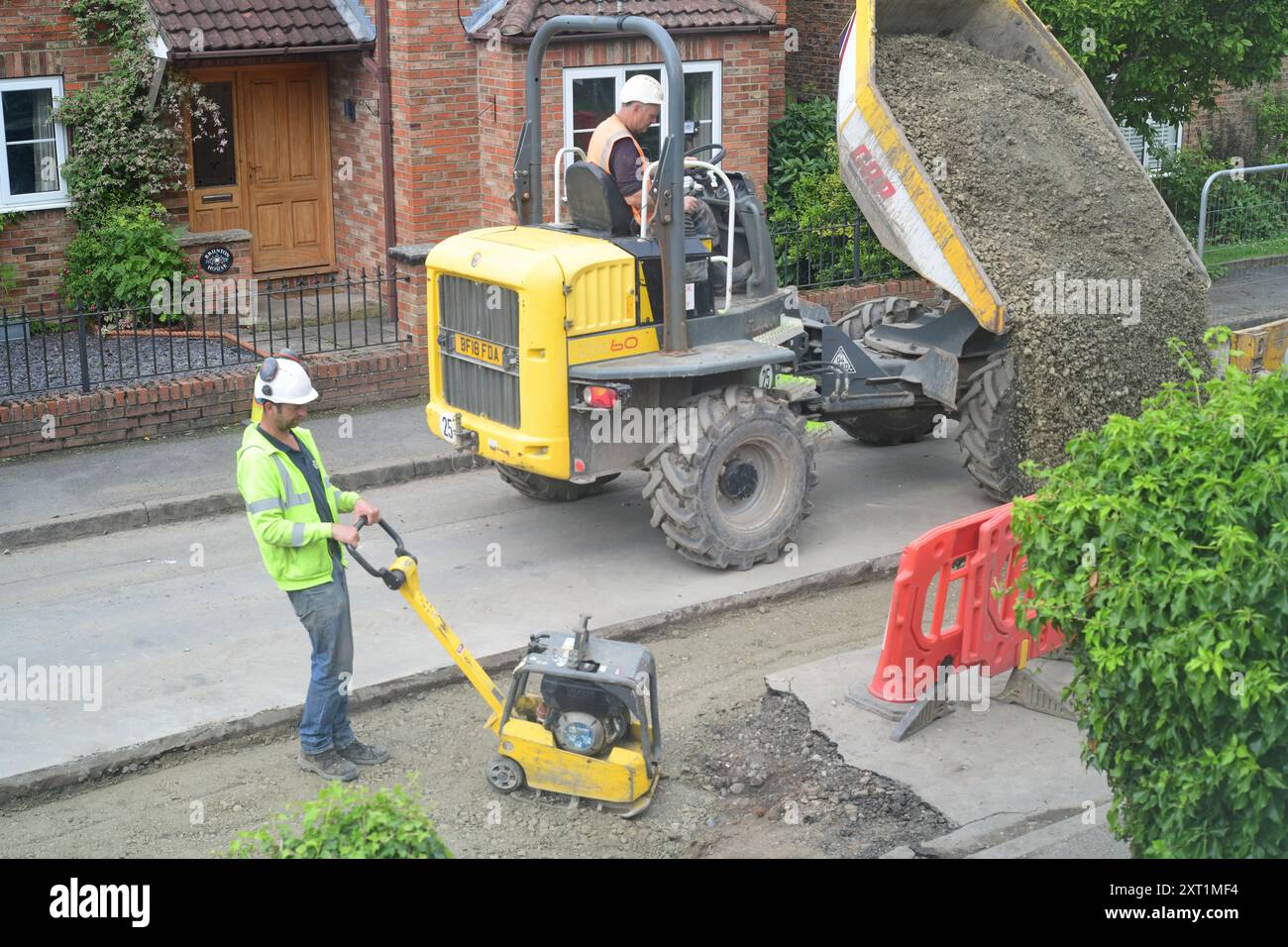 Ingegnere che utilizza un compattatore a rulli presso la nuova linea di tubi sotto la strada principale per fermare le inondazioni nel villaggio di Ellerton York Yorkshire Regno Unito Foto Stock