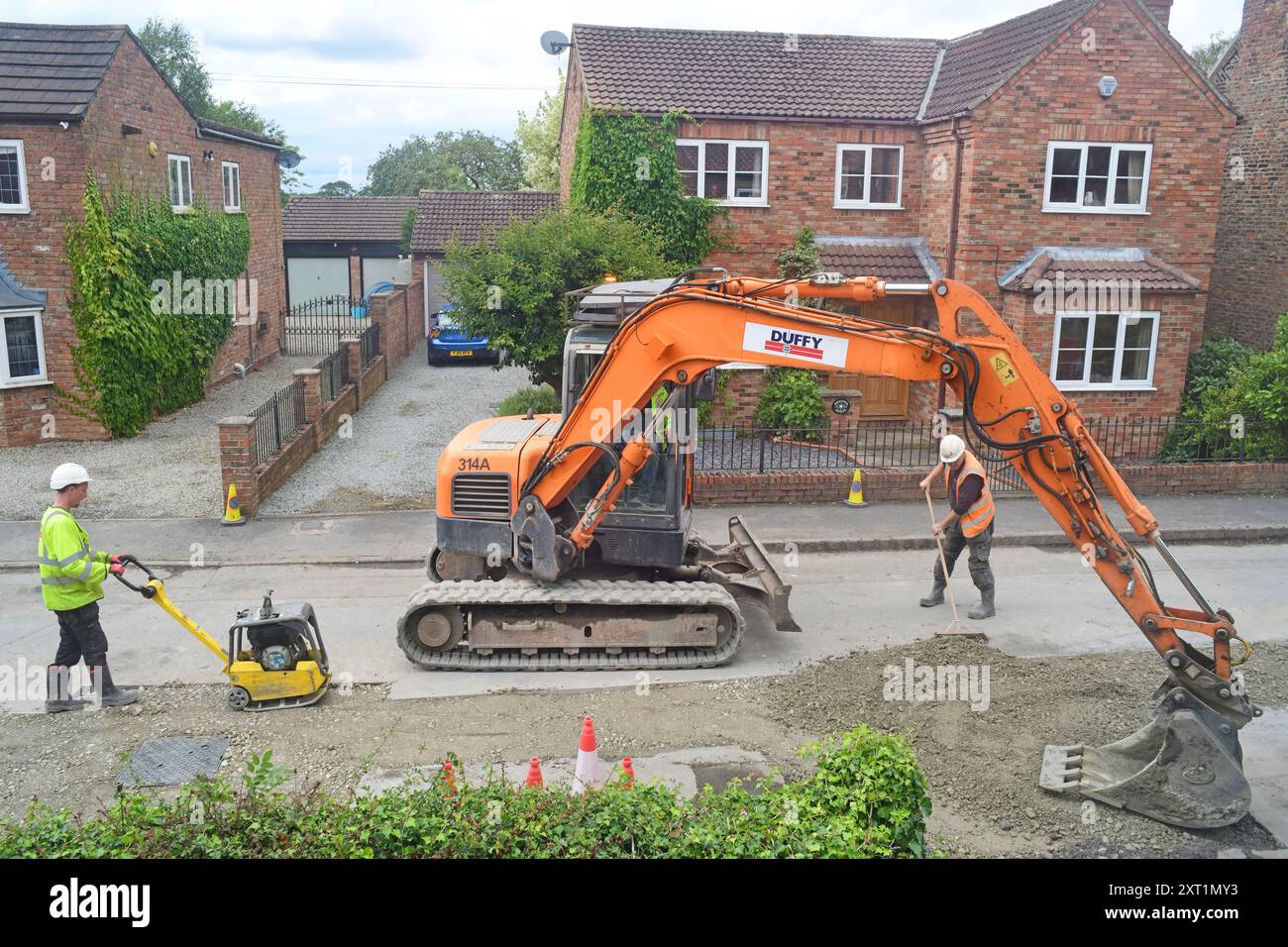 Ingegneri che installano una nuova linea di tubi sotto la strada principale per fermare le inondazioni nel villaggio di Ellerton York Yorkshire Regno Unito Foto Stock