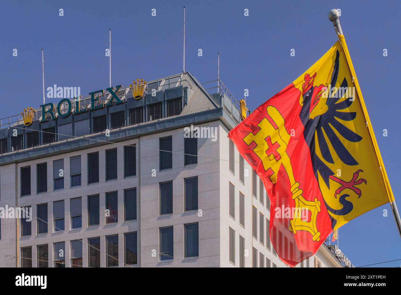 Geneve, Svizzera, 09.02.2023: Bandiera del Cantone di Ginevra che sventola contro gli uffici e la sede della Rolex a Ginevra Foto Stock