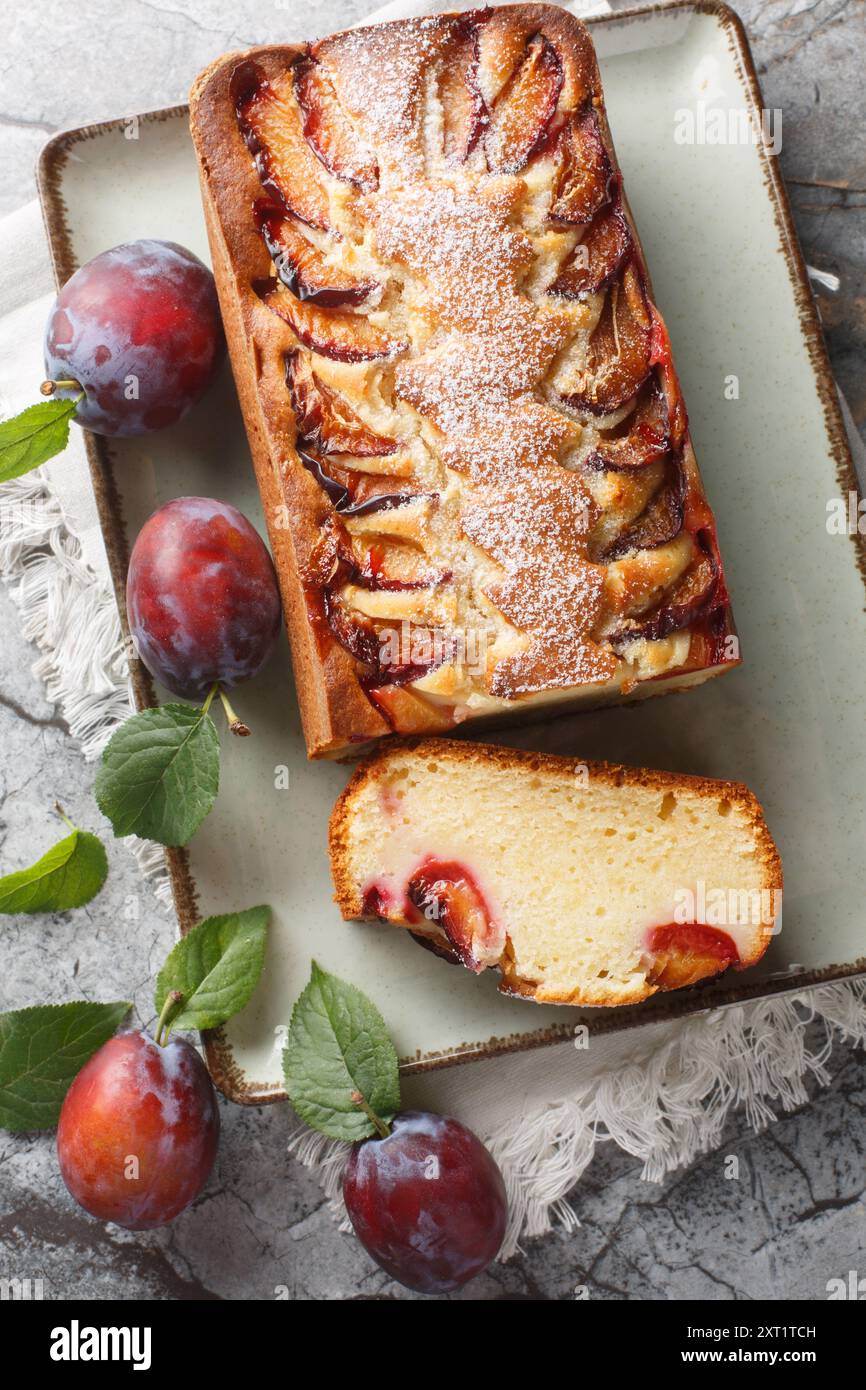 La gustosa torta di prugne allo yogurt, preparata con yogurt e olio d'oliva, è leggera, umida e deliziosa per il brunch e il primo piano del dessert sul piatto del tavolo. Verticale Foto Stock