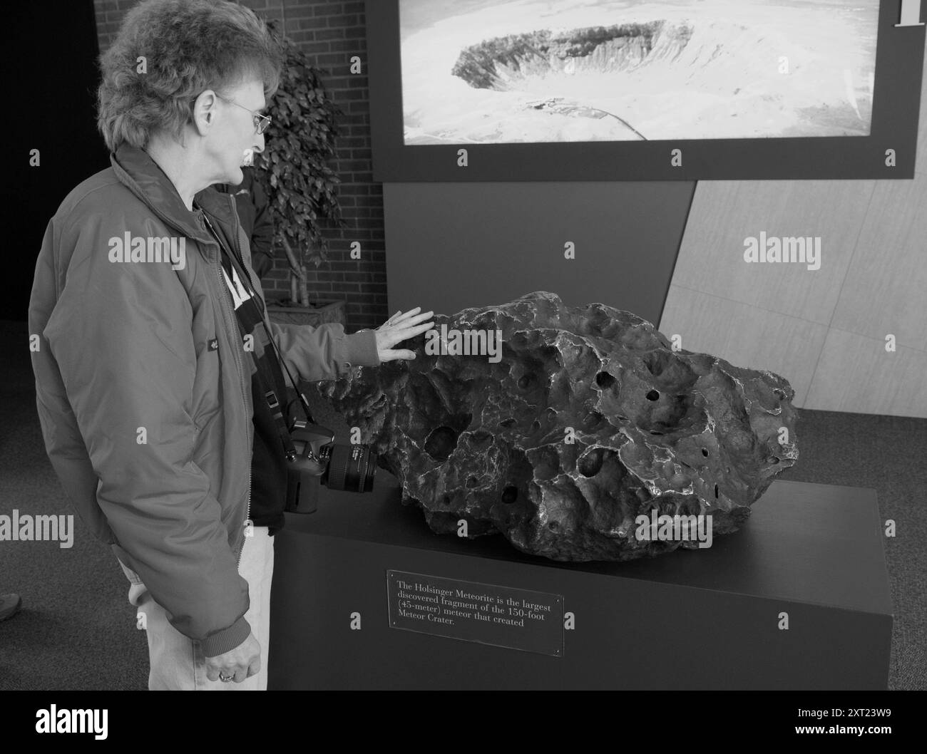 Donna caucasica di età compresa tra i 50 e i 60 anni, sentendo l'Holsinger Meteorite al Meteor Crater, situato sulla Route 66, appena fuori la i-40 vicino a Winslow, Arizona. STATI UNITI Foto Stock