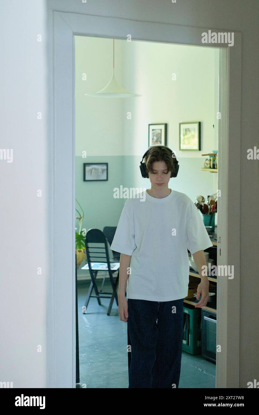 Giovane con le cuffie in piedi in una porta all'interno di una stanza ben illuminata. Bola02814 Copyright: XConnectxImagesx Foto Stock