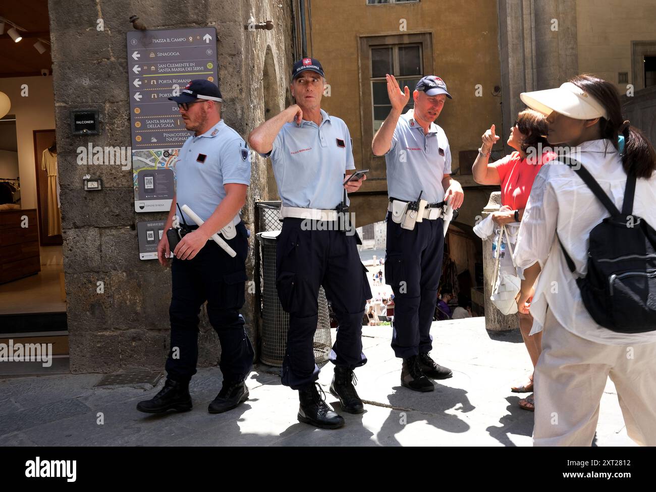 Gli agenti della polizia Municipale che danno indicazioni per i turisti a Siena, Toscana, Italia Foto Stock