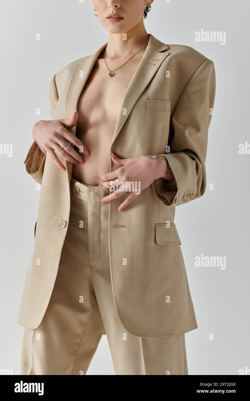 Una donna con un blazer beige e pantaloni coordinati si posa in tutta sicurezza. Foto Stock
