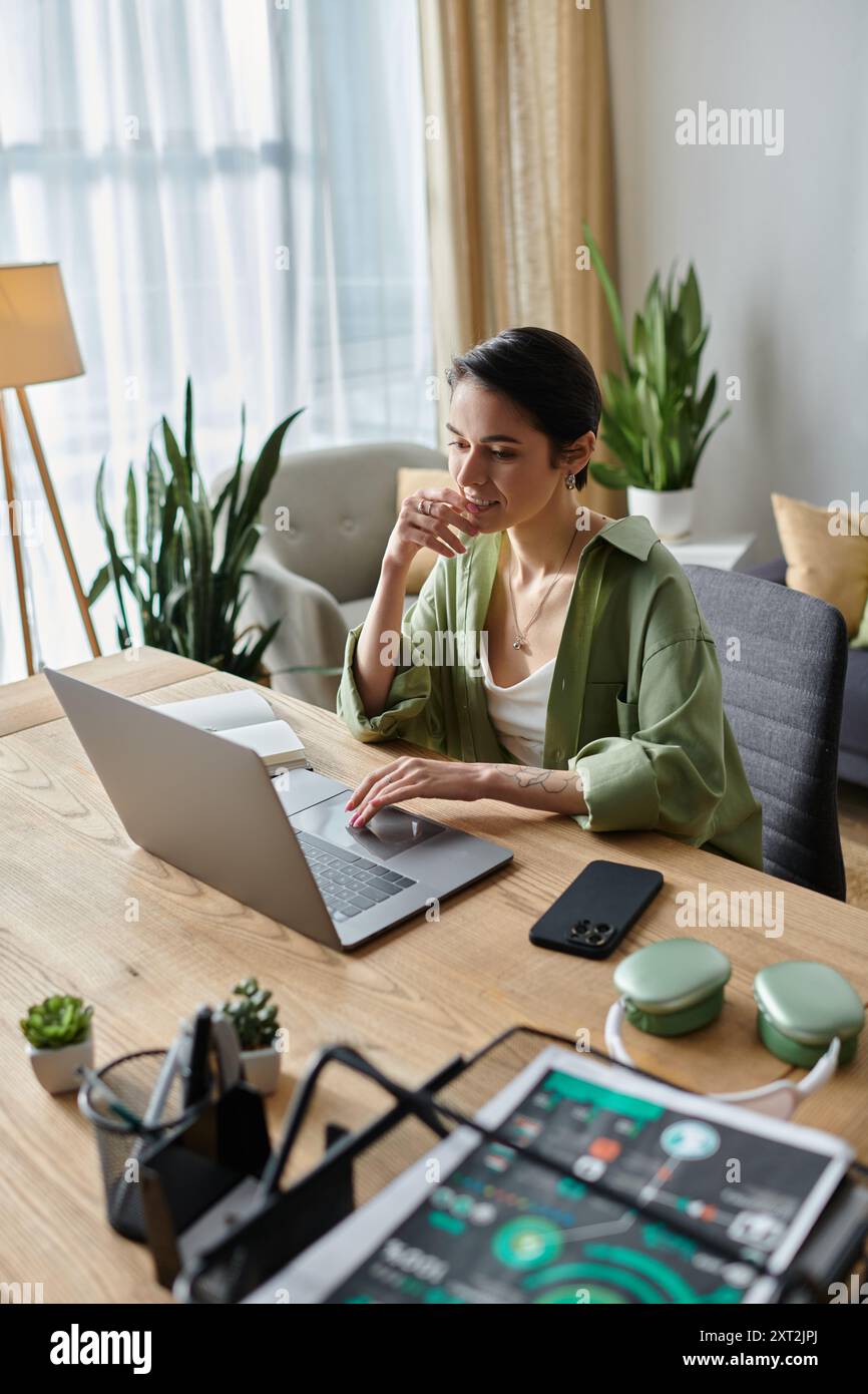 Una donna siede a una scrivania nel suo ufficio domestico e lavora sul suo computer portatile. Foto Stock