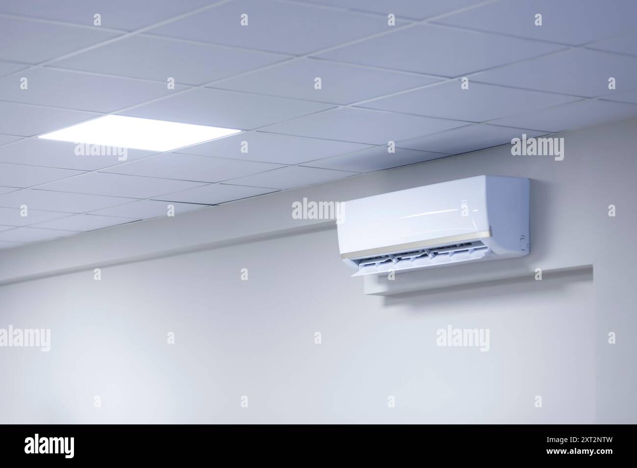 Aria condizionata a parete in una camera con soffitto piastrellato e moderna tecnologia di controllo della temperatura. Copia spazio. Foto Stock