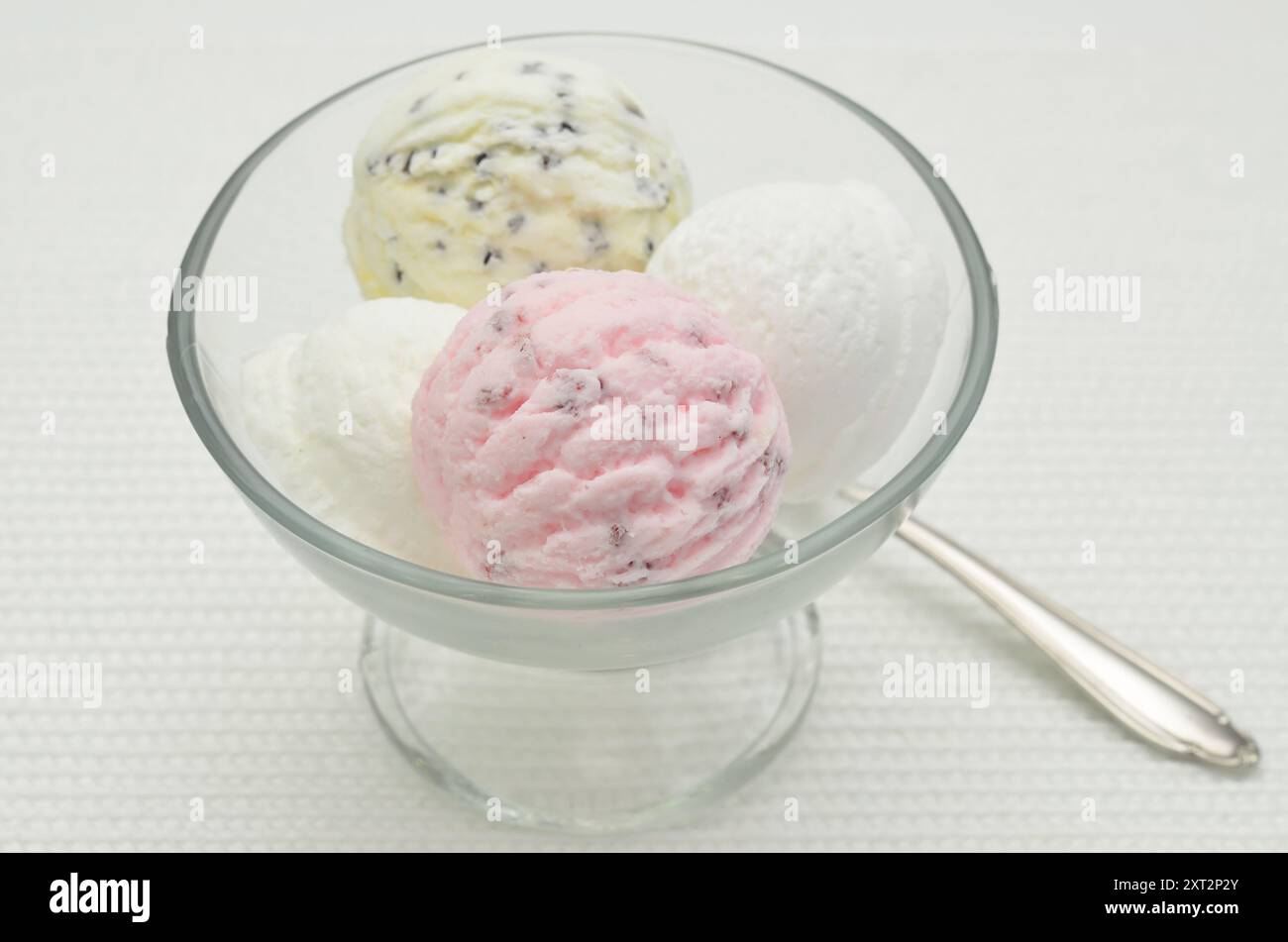 Cucchiai di gelato in un recipiente di vetro, da vicino, isolato su sfondo bianco Foto Stock