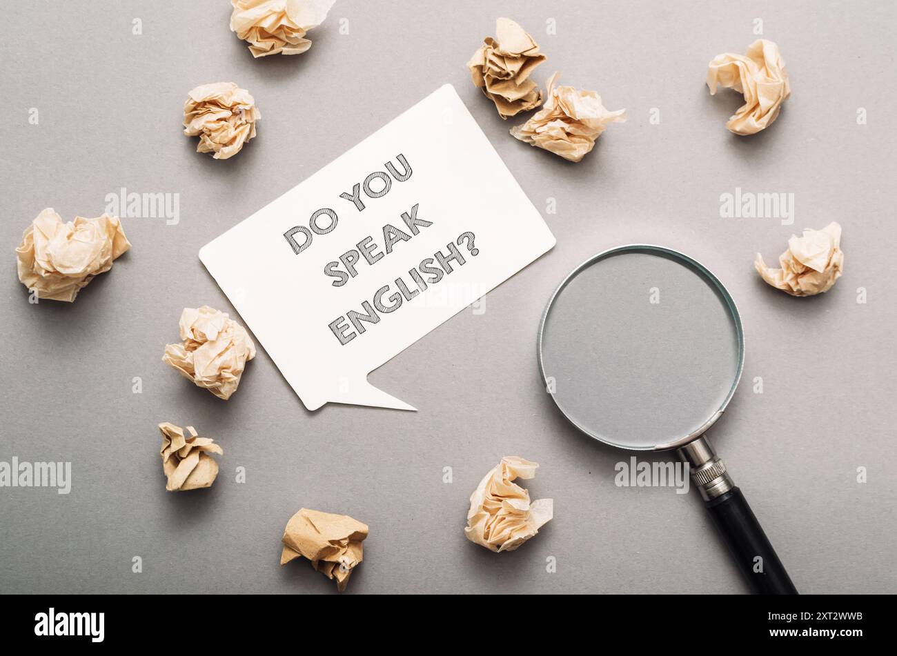 Un segno che dice "parla inglese" è circondato da carta straccia. La carta grattugiata è sparsa intorno al segno, creando un disordine Foto Stock