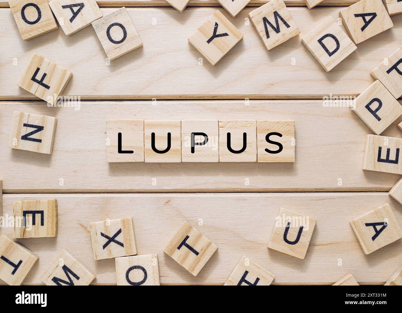 Una tavola di legno con un mazzo di lettere di legno sparse intorno ad essa. Le lettere scrivono la parola Lupus Foto Stock
