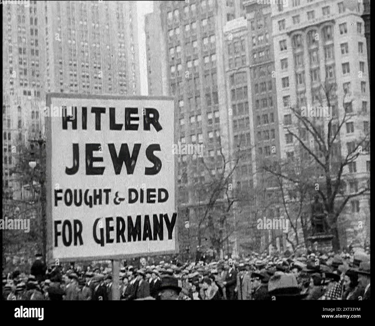 Antifascisti americani che marciano con un cartello che recita: "Hitler - ebrei combatterono &amp; morirono per la Germania”, 1933. Persone che protestano contro la persecuzione nazista degli ebrei. "Ovunque nel mondo, dove c'erano grandi comunità ebraiche, c'erano manifestazioni, proteste, e da nessuna parte le voci erano più alte che negli Stati Uniti. Ma ahimè, le semplici parole non rovesciano un tiranno”. Da "Time to Remember - The Time of the Monster", 1933 (Reel 4); un documentario sugli eventi del 1933, Rise of Roosevelt e Hitler. Foto Stock