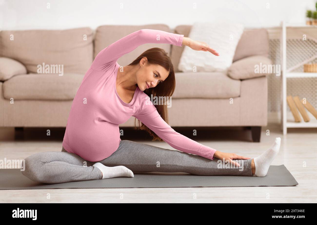 Calma la donna incinta facendo esercizi di stretching a casa Foto Stock