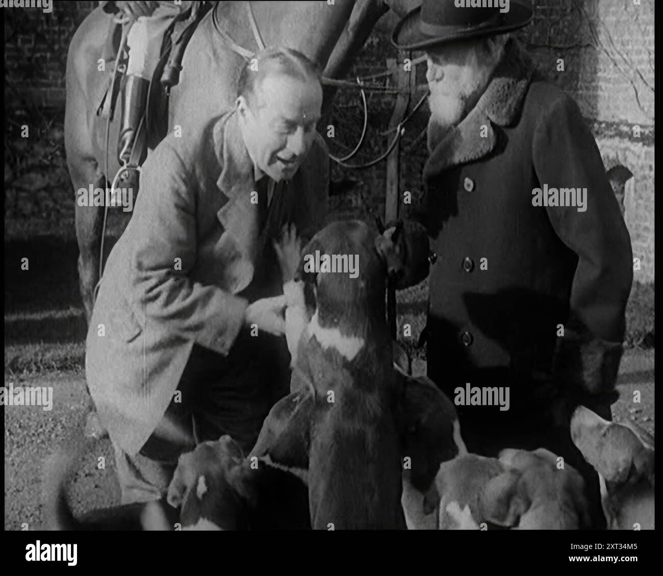 Il primo ministro Stanley Baldwin Petting Dogs. Accanto a lui, a male Civilian si erge accanto a un cavallo, 1924. Da "Time to Remember - A Trip to Europe", 1924 (Reel 2); uno sguardo alla vita politica e sociale in Europa e oltre nel 1924. Foto Stock