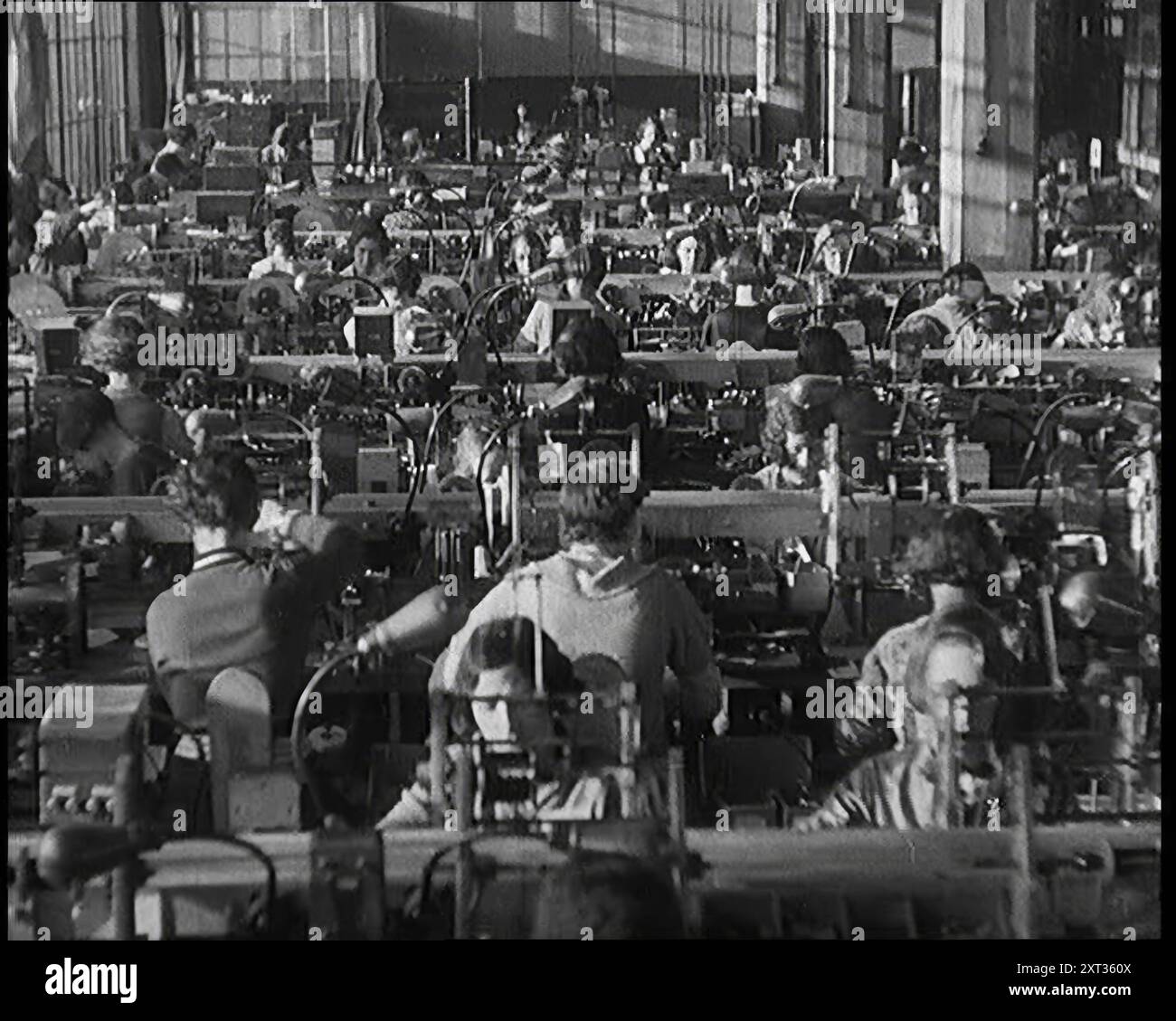 Donne civili che lavorano su una linea di produzione di fabbrica, 1931. "Sally Smith [cioè la donna britannica media] era più probabile che non fosse una lavoratrice ora, impiegando le sue dita agili lungo quelle... linee di produzione di massa. E non importa quanto fosse normale il lavoro, raramente sembrava annoiarsi con esso. Da Time to Remember - A New era, 1931 (Reel 2); documentario sul mondo nei primi anni '1930 Foto Stock