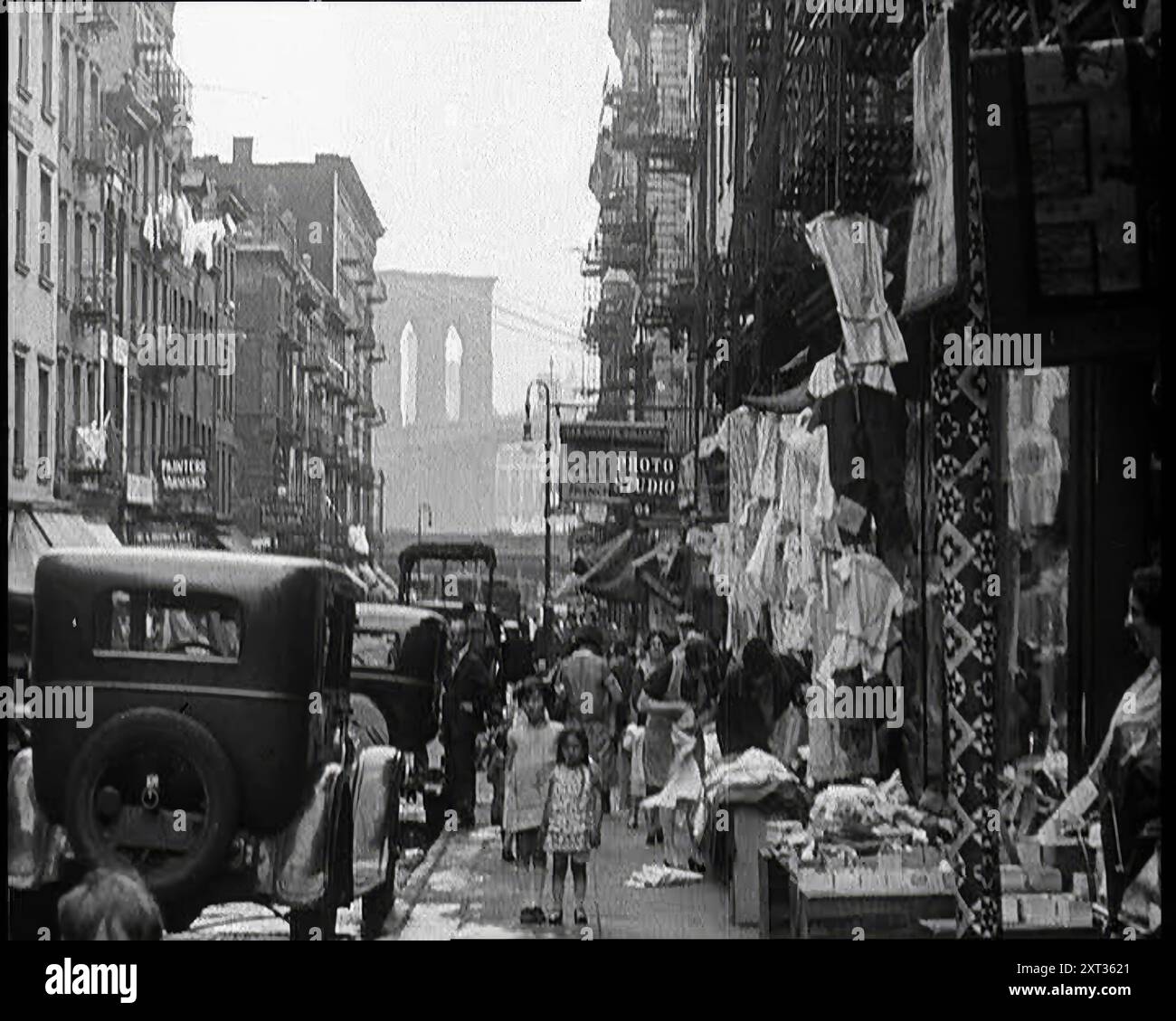 Street View of Street Market che vende vestiti a New York City, 1932. Il potere dell'uomo di amministrare la ricchezza era molto indietro rispetto alla sua capacità di produrla. Quelli che l'hanno prodotta condividevano solo una parte dei suoi benefici. Sotto i pinnacoli [di ricchezza], le pareti grigie, gli appartamenti e i pedone. Da "Time to Remember - Around the Corner", 1932 (Reel 2); diario degli eventi del 1932 negli Stati Uniti d'America - Franklin Roosevelt diventa presidente. Foto Stock