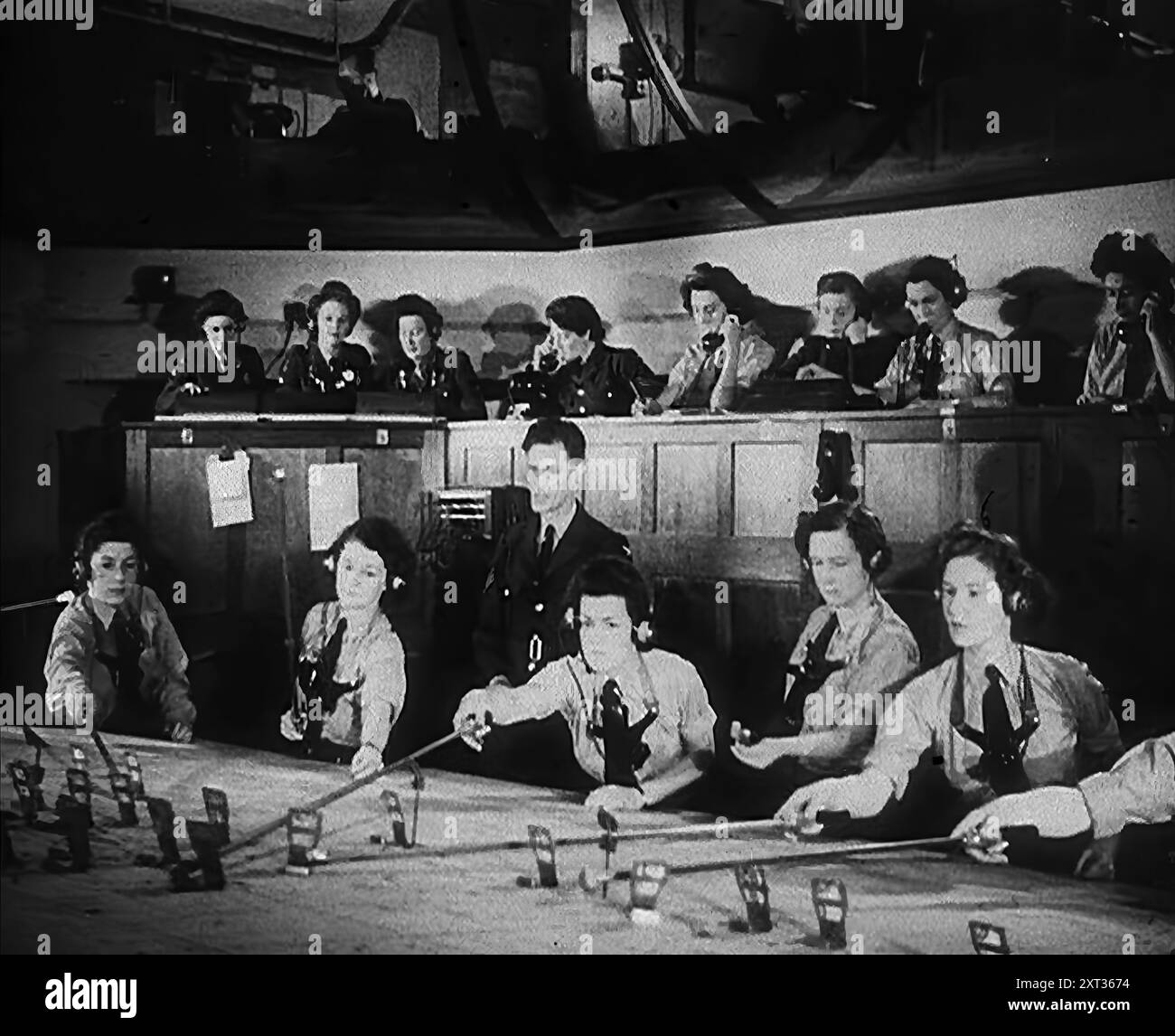 Plotter WAAF Working with Plotting Equipment, 1940. Regno Unito durante la seconda guerra mondiale: Donne che monitorano i bombardamenti tedeschi. "Ottanta più [aerei nemici], assemblando su aree Amiens, Abbeville. Altri sessanta, vicino a Dieppe. Controllo consigliato". I primi rapporti radar tendono verso la probabilità che gli obiettivi siano aeroporti di caccia a est e a sud-est di Londra. In altre parole, per Control, sembra lo stesso di stamattina. Ma e' troppo presto per giudicare. Potrebbe essere Londra stessa. "Tutti gli squadroni disponibili sono pronti. Sentiamo dal corpo degli osservatori non appena pos Foto Stock