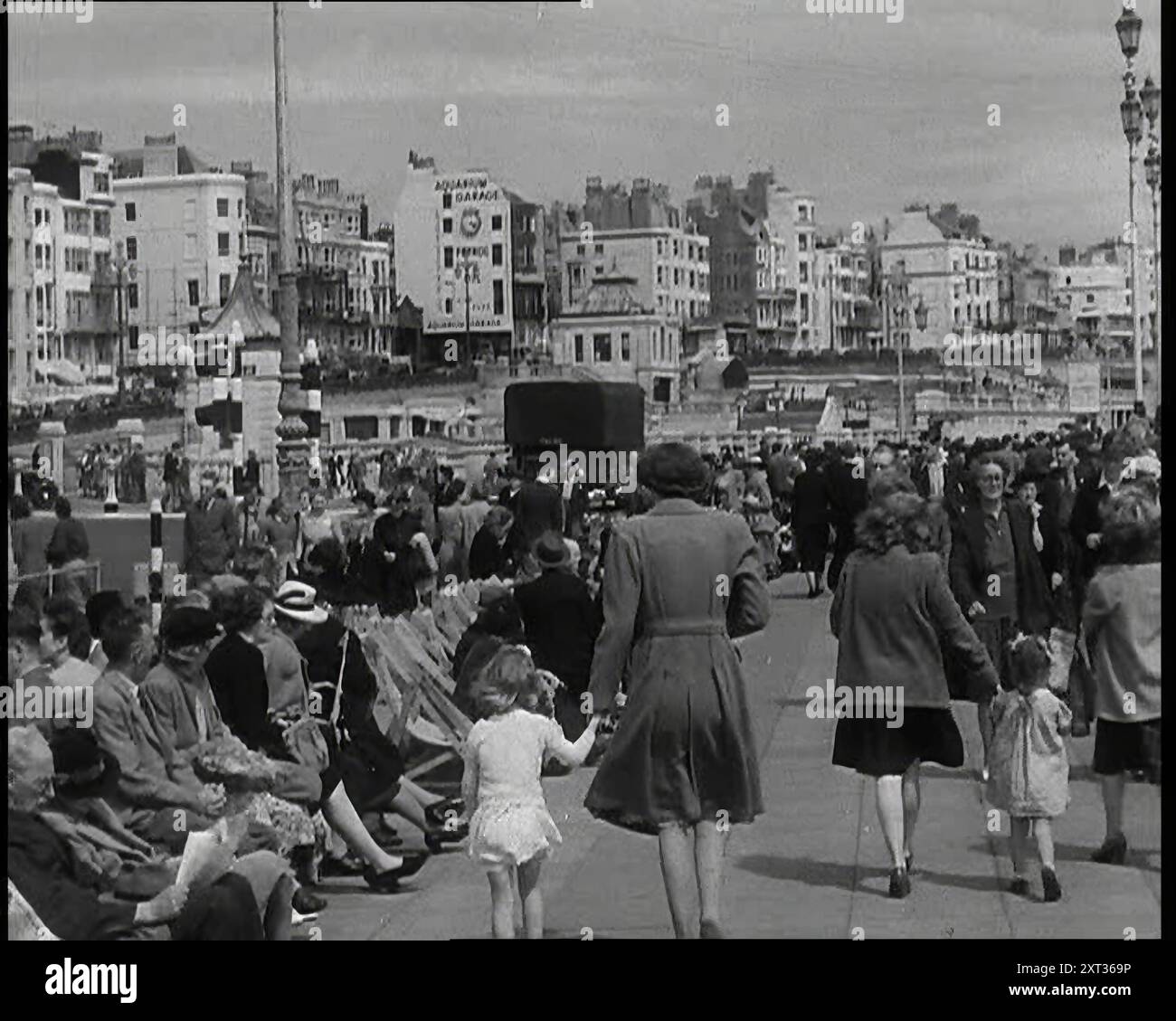 Turisti britannici che camminano lungo la Promenade o seduti su sdraio a Brighton con il Brighton Aquarium e la Houses of Marine Parade sullo sfondo, 1938. Da "Time to Remember - Wind Up Week", 1938 (Reel 3); documentario sul 1938 - le persone diventano consapevoli della crescente minaccia della guerra. Foto Stock