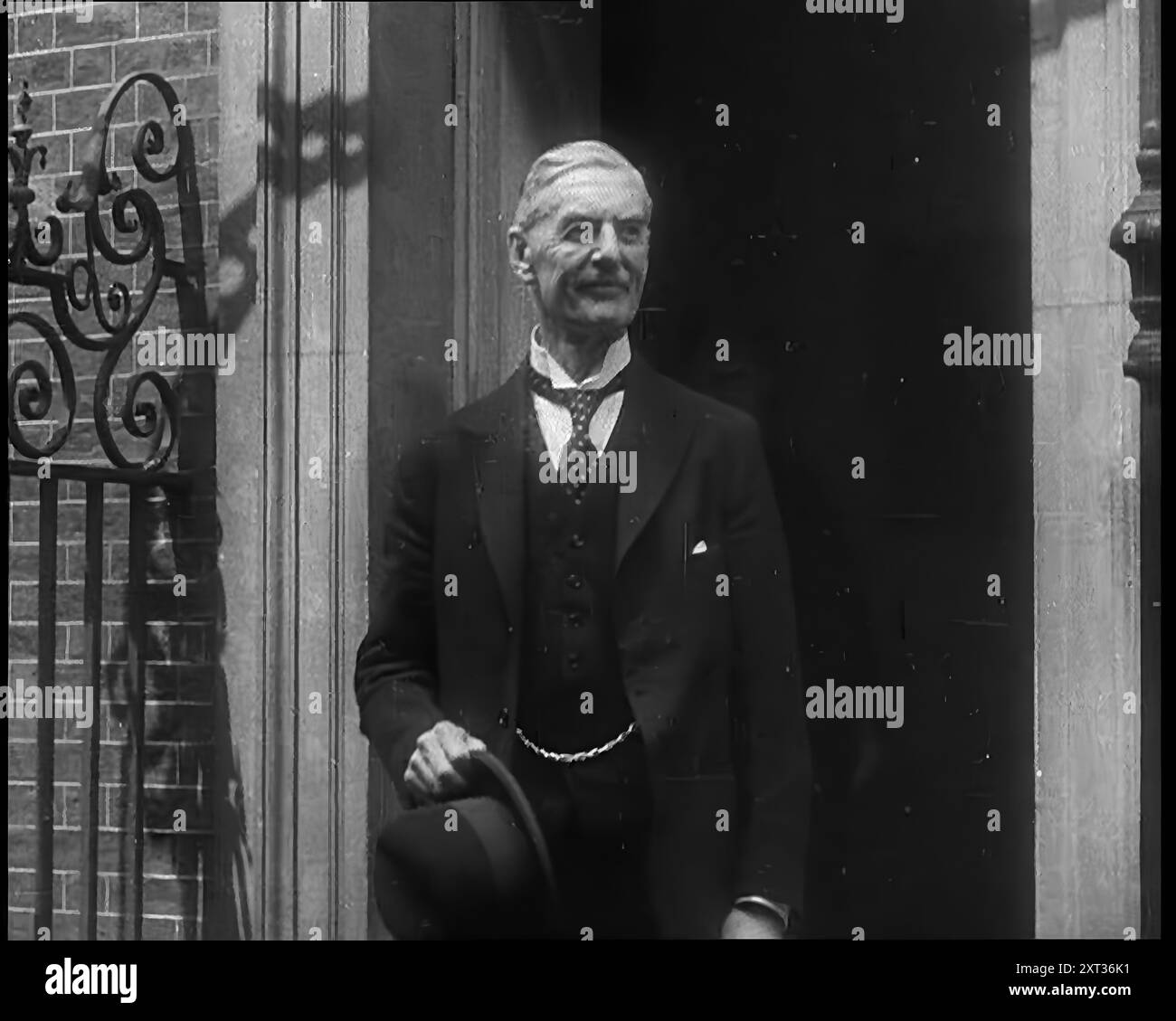 Il primo ministro britannico Neville Chamberlain ha lasciato il numero 10, Downing Street, per l'ultima volta, 1940. Seconda guerra mondiale. "Sei stato seduto qui troppo a lungo per tutto il bene che hai fatto. Se ne vada, dico, e lasciamo che abbiamo finito con te. Nel nome di Dio andate!" E così se n'è andato. Un uomo il cui ombrello era diventato il simbolo umido di un modo di pensare obsoleto”. Da "Time to Remember - Run Rabbit Run", 1940 ( Reel 2); film documentario sugli eventi dei primi mesi del 1940. Foto Stock