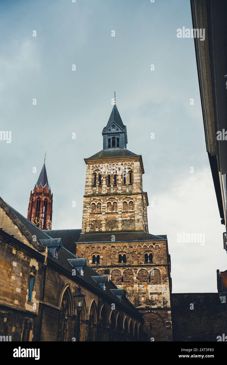 Dal basso un'architettura storica di Amsterdam con particolare attenzione a una chiesa splendidamente invecchiata, caratterizzata da intricate murature e una torreggiante guglia sotto un mese Foto Stock