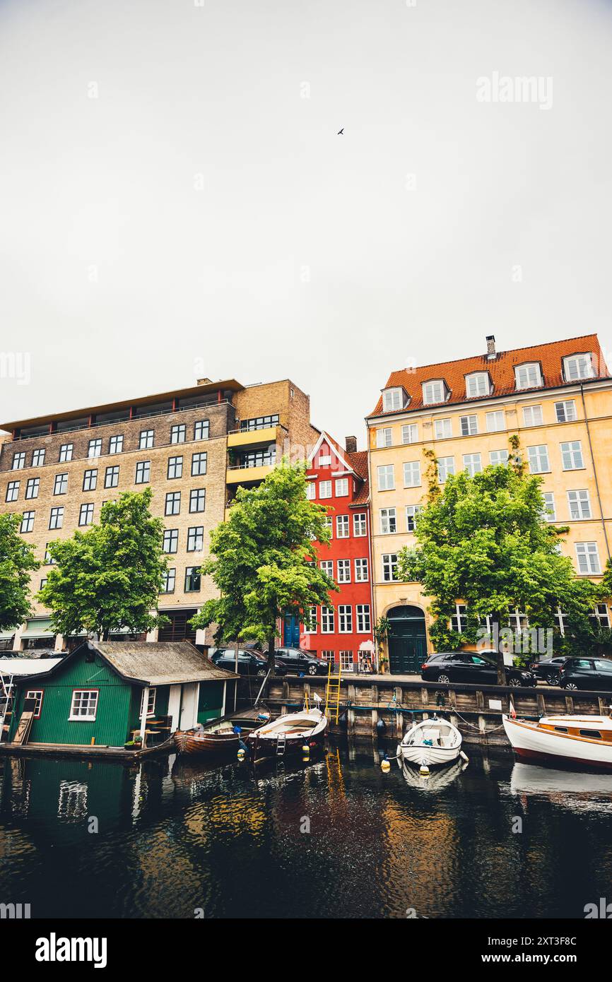 Una vista panoramica di un canale di Copenaghen, fiancheggiato da vivaci edifici storici e barche da diporto. Questa immagine cattura l'affascinante paesaggio urbano e l'ar Foto Stock