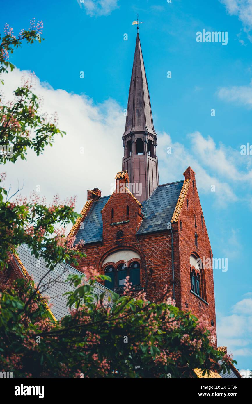 Chiesa suggestiva a Copenaghen, Danimarca, evidenziata da vibranti fioriture primaverili. Ideale per mostrare l'architettura europea e l'estetica dei viaggi. Foto Stock