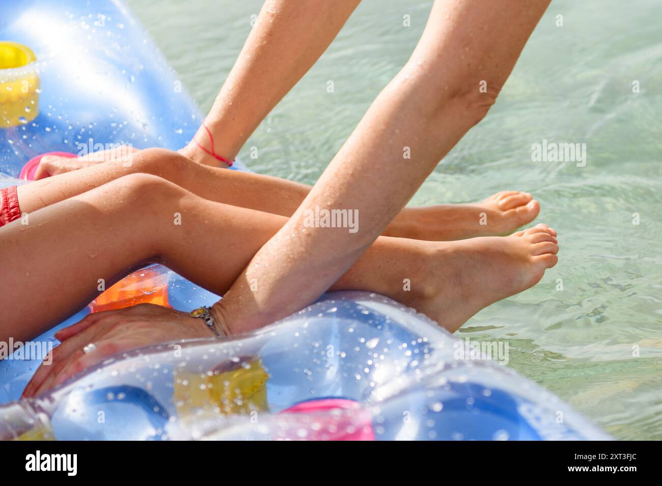 Due persone si godono una giornata di sole su un galleggiante gonfiabile in acqua fresca e limpida. La scena cattura un senso di svago e divertimento estivo, mettendo in risalto Foto Stock