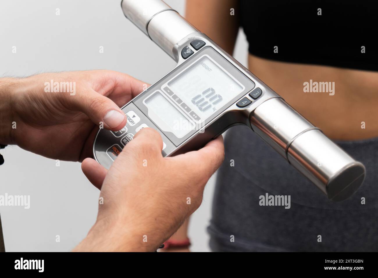 Una persona utilizza un analizzatore portatile di grasso corporeo per valutare la composizione corporea, concentrandosi sul monitoraggio della salute e del fitness il dispositivo è progettato per fornire infor Foto Stock