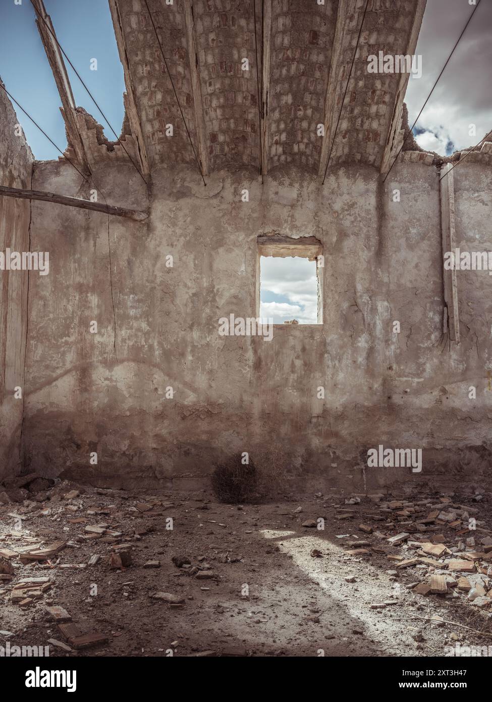 Interno in decadenza di una struttura abbandonata con pareti sbriciolate, soffitto in cemento esposto e pavimento disseminato di detriti, che trasporta la desolazione e il pa Foto Stock
