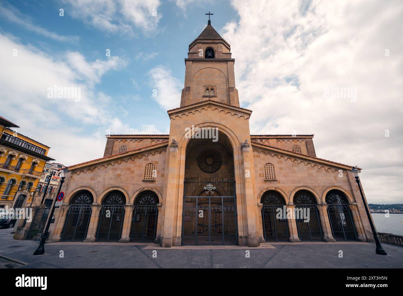 Vista maestosa di una facciata tradizionale della chiesa di Gijon, Spagna, con architettura storica contro un suggestivo cielo nuvoloso. Foto Stock
