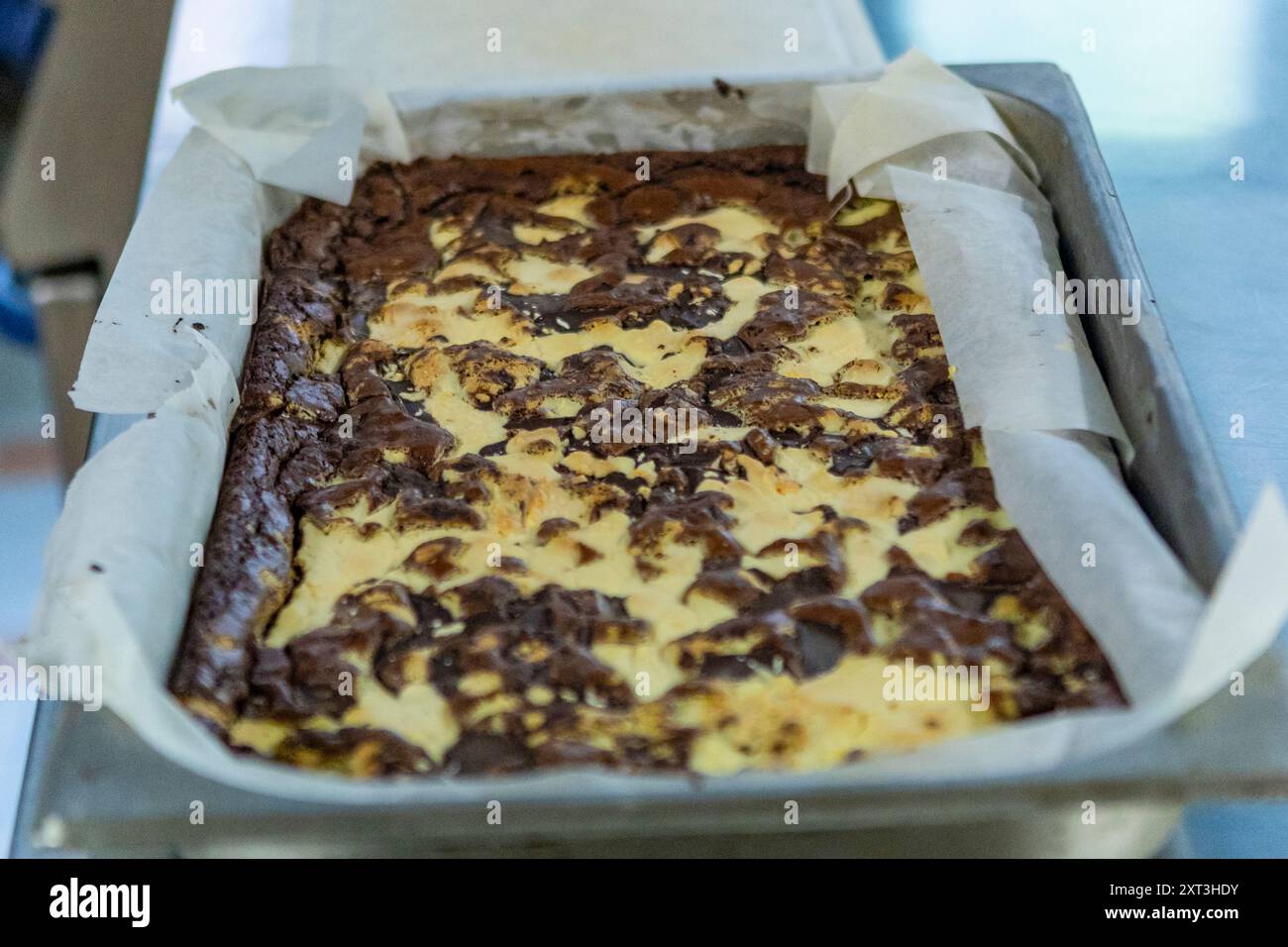 Vassoio in metallo con brownie marmorizzati appena sfornati con vortici di vaniglia e pastella di cioccolato, rivestiti con carta pergamena Foto Stock