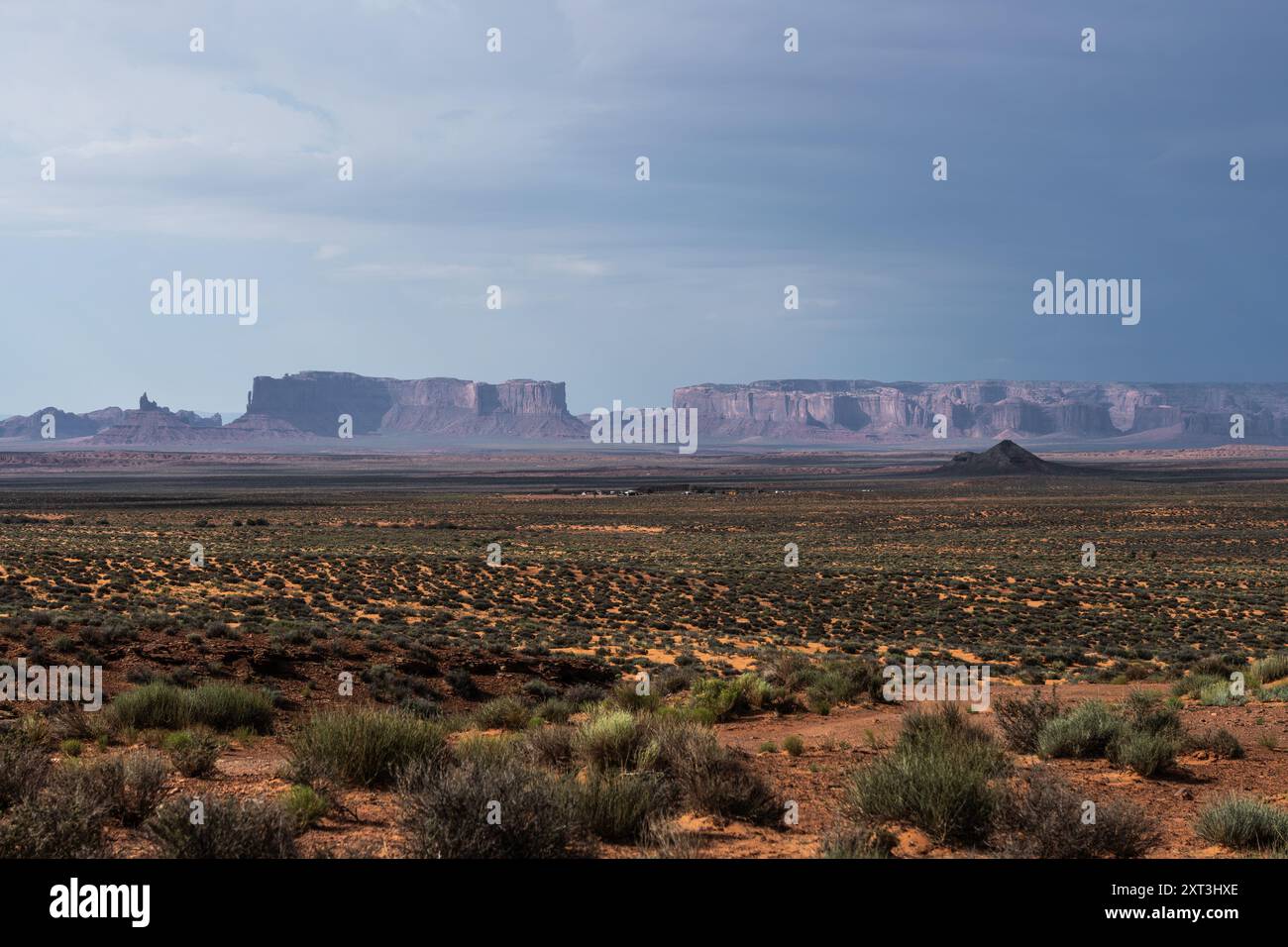 Immagine suggestiva della Monument Valley sotto un cielo scuro, che suggerisce una tempesta imminente, con vaste pianure aride e iconiche arenarie Foto Stock