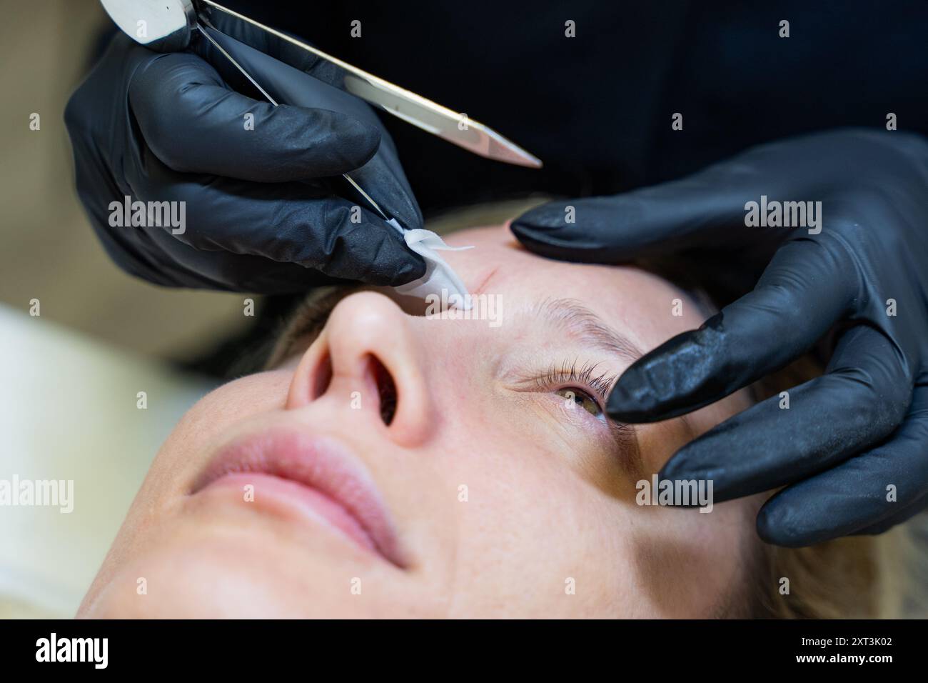 Un estetista misura e disegna meticolosamente le caratteristiche facciali per la microblading al fine di creare un design personalizzato e simmetrico delle sopracciglia per il TH Foto Stock