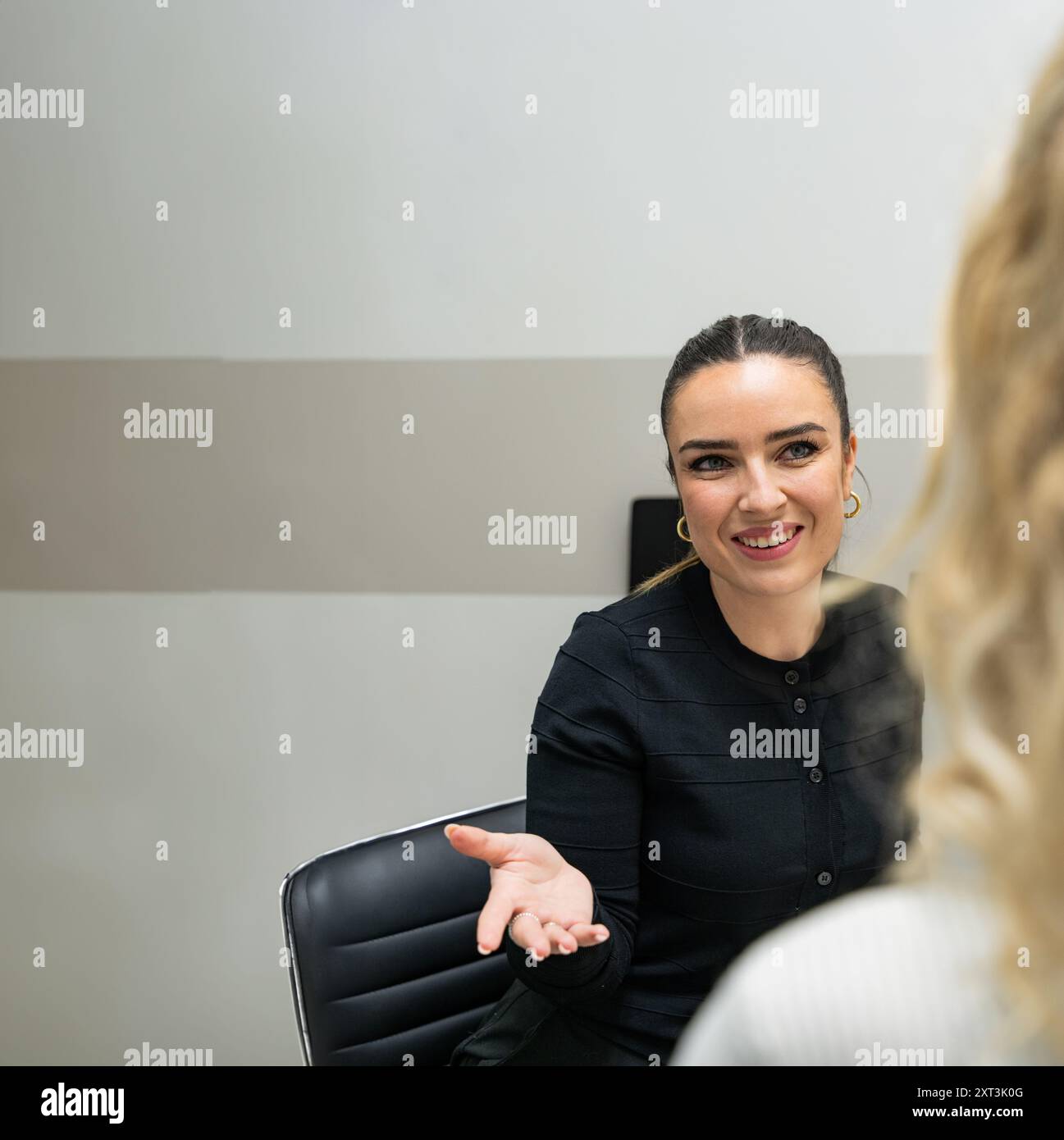 Un estetista professionista viene visto impegnato in una conversazione con un cliente, discutendo il processo e i vantaggi della microblading in un moderno salon setti Foto Stock