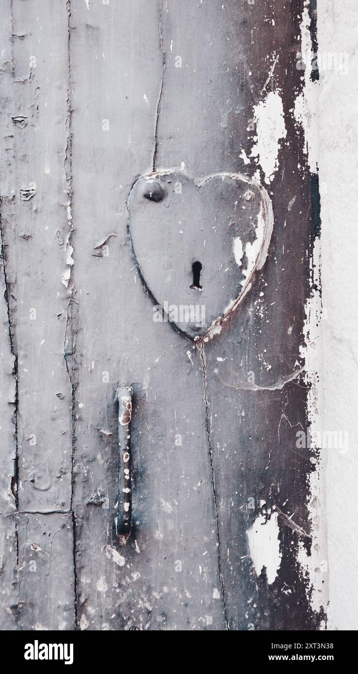 Antica porta con serratura a forma di cuore e maniglia. Foto Stock