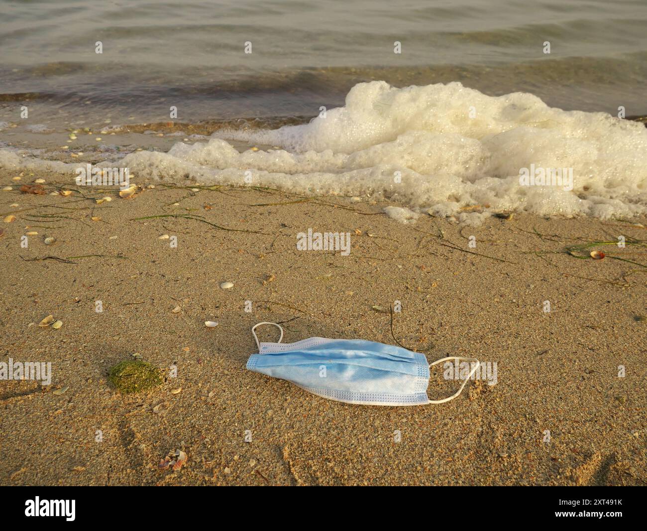 Un primo piano di una maschera sulla spiaggia- inquinamento ambientale e concetto di covid-19 Foto Stock