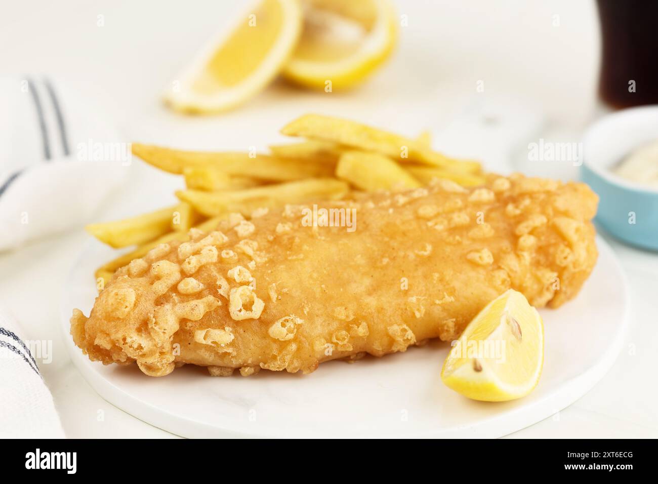 Pesce e patatine fritte. Filetto di pesce fritto con patatine fritte e salsa di tartara su sfondo bianco brillante. Foto Stock