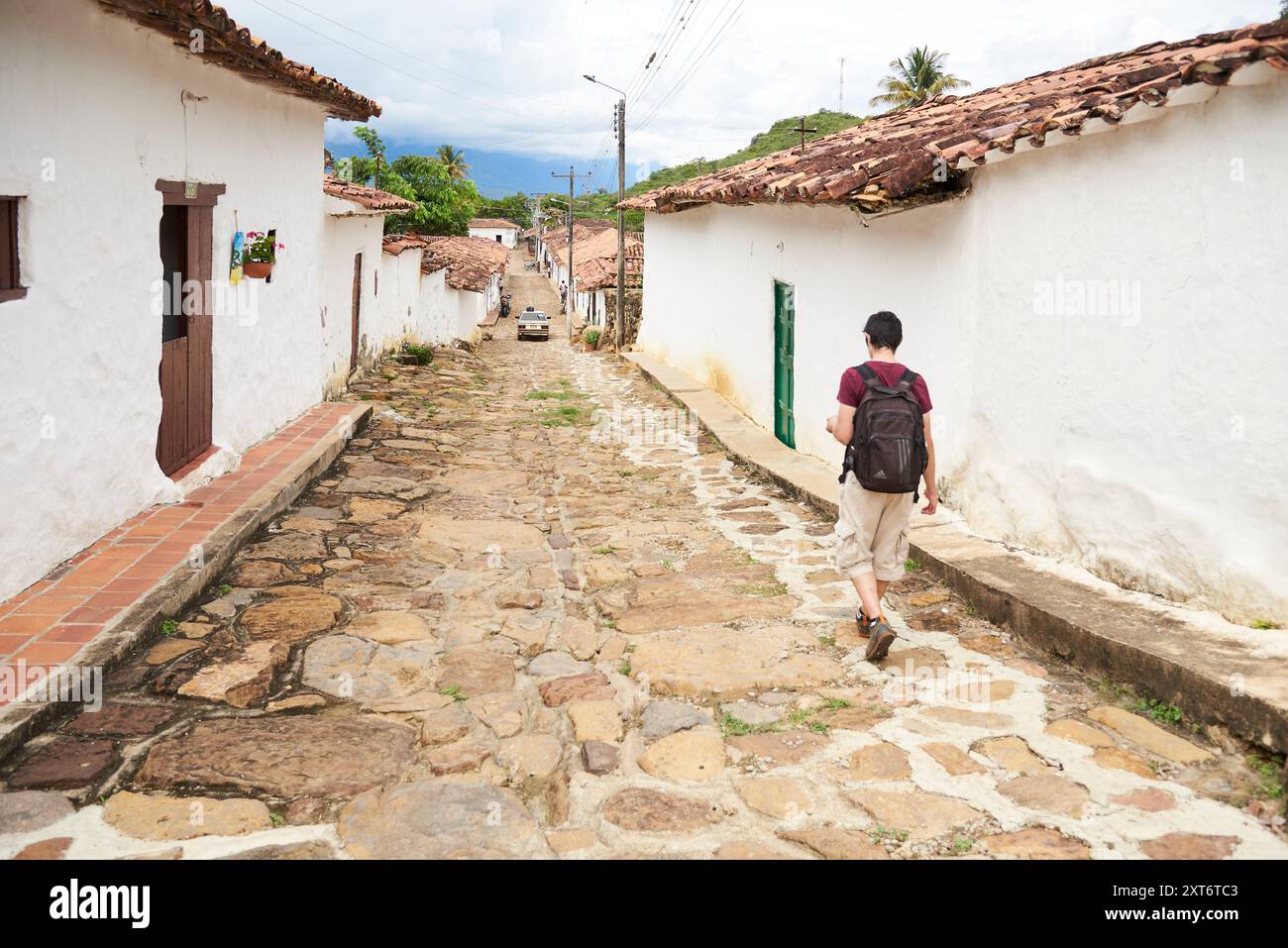 Guane, Santander, Colombia; 26 novembre 2022: Giovane visto da dietro camminando rilassato lungo una strada in questa pittoresca città coloniale. Foto Stock