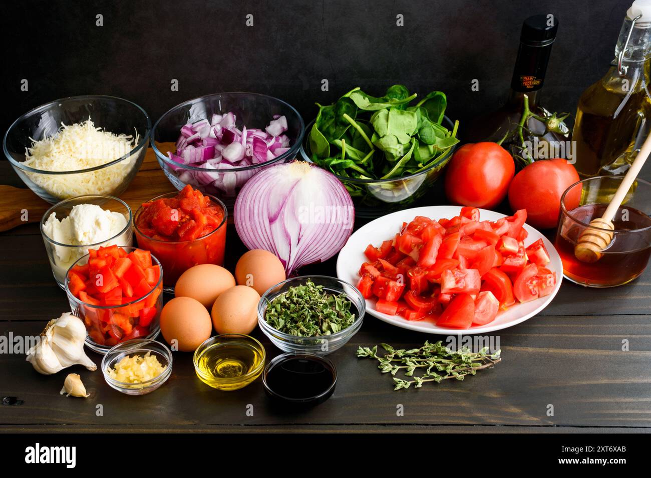 Ingredienti della Parmigiana Shakshuka di melanzane preparate: Ingredienti della cucina fusion tritati, tritati e misurati su un tavolo di legno Foto Stock