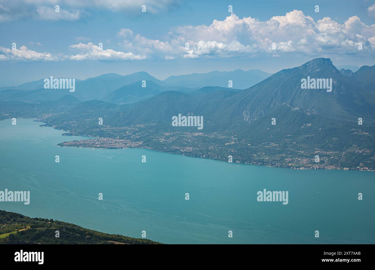 Vista panoramica in direzione ovest del Lago di Garda blu e delle montagne circostanti da un'altezza vicino a Prada, Italia. Foto Stock