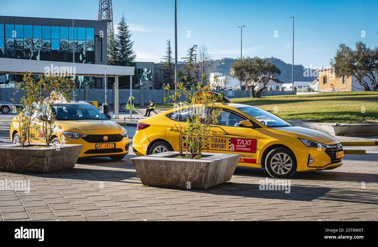 Scena di strada con taxi parcheggiati presso l'aeroporto internazionale di Tirana in Albania. Taxi parcheggiati su una strada in attesa dell'arrivo dei turisti all'aeroporto. Foto Stock